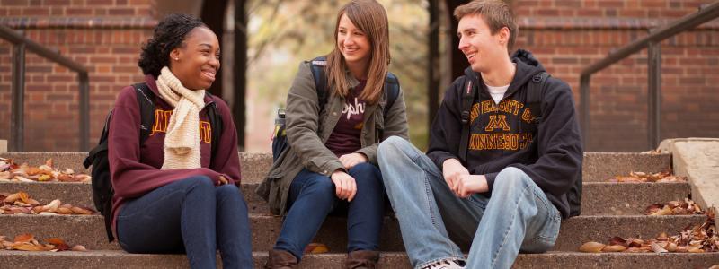 UMN students sitting on stairs smiling and talking